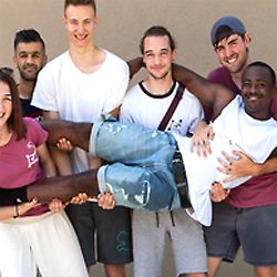 Fünf junge Menschen halten einen sechsten Mann auf Armen noch